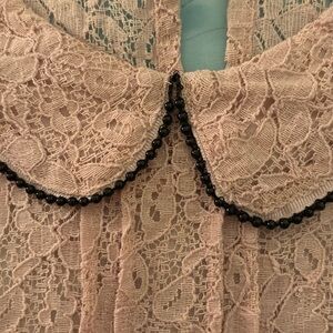 Sleeveless lace top with black bead trim on collar.